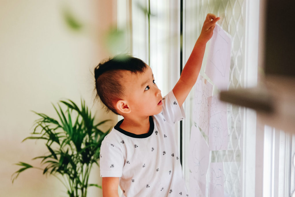 little boy reaching up at a window