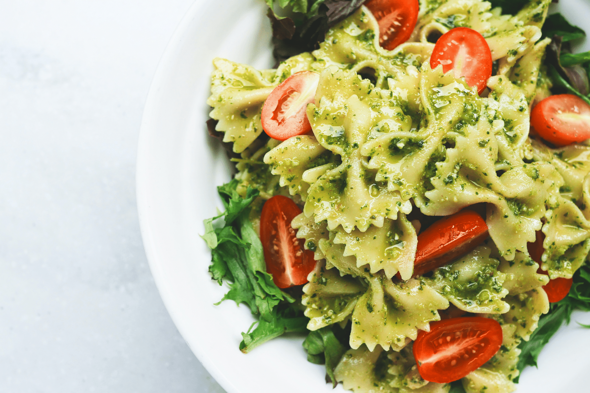 bowtie pasta with pesto and cherry tomatoes in a bowl