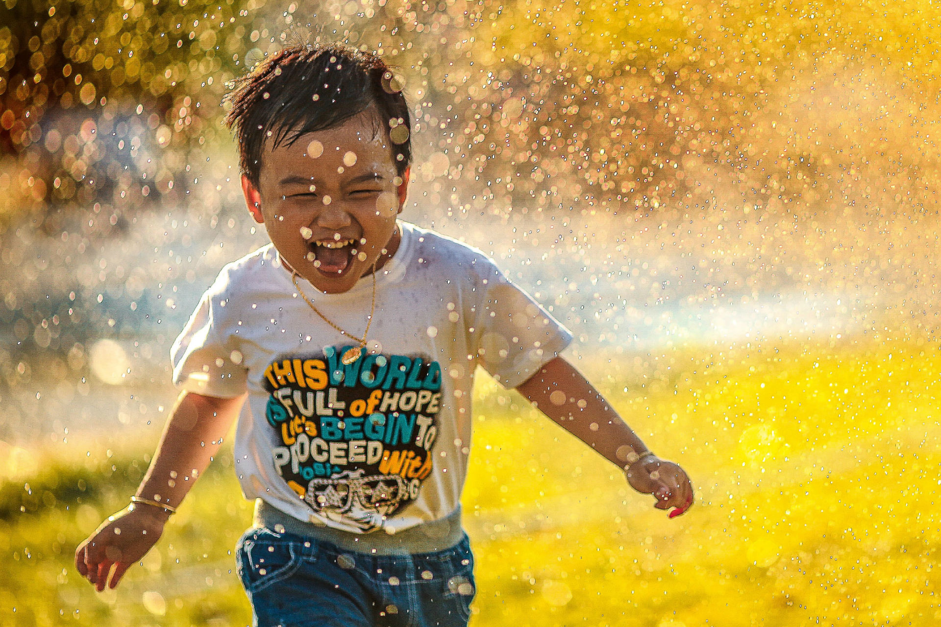 little boy running through sprinkler