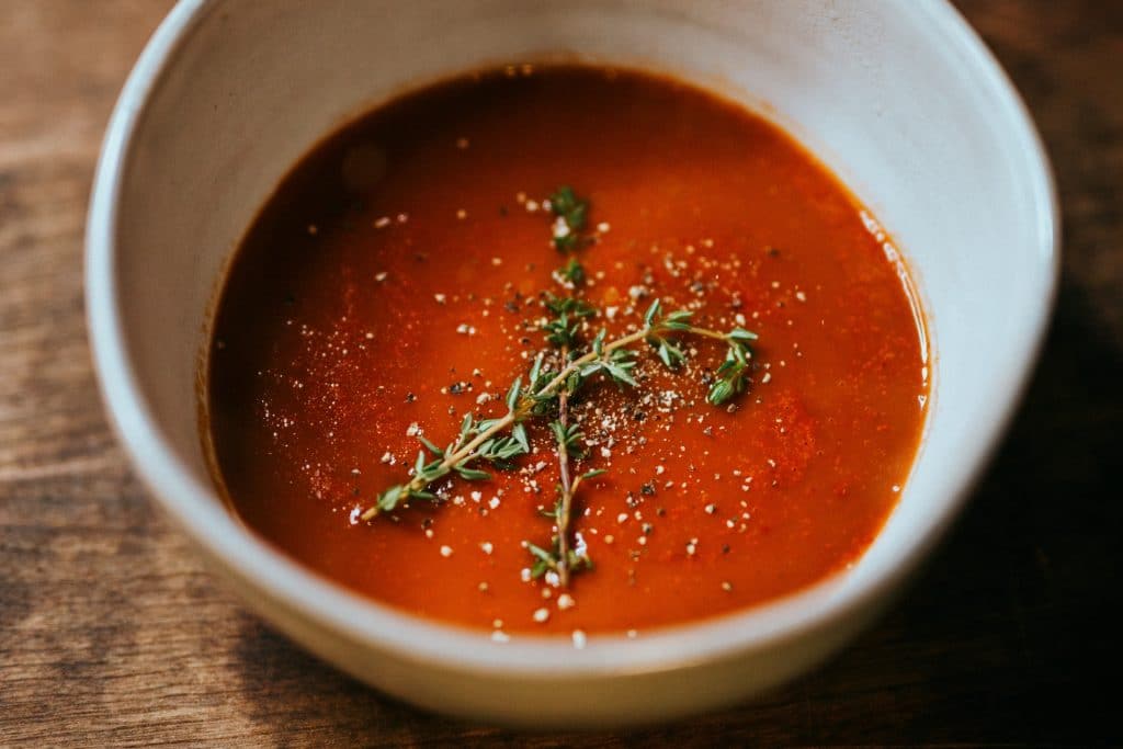 bowl of tomato soup with thyme sprigs as garnish
