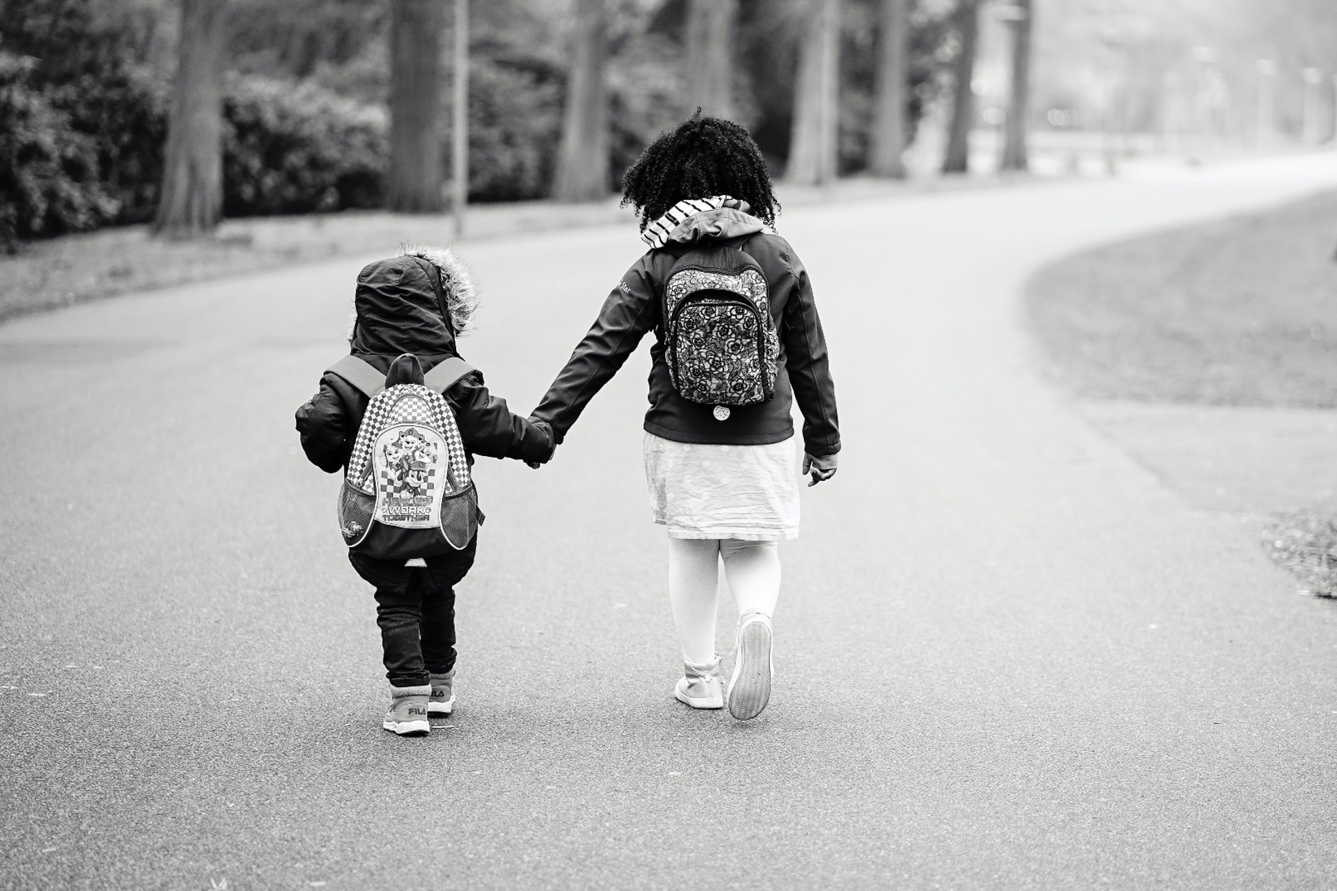 two kids walk to school wearing backpacks