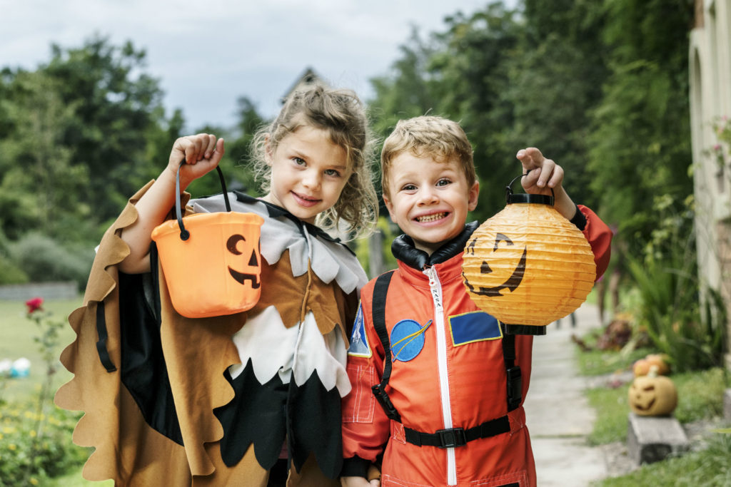 Kids dressed up in Halloween costumes with trick-or-treating buckets