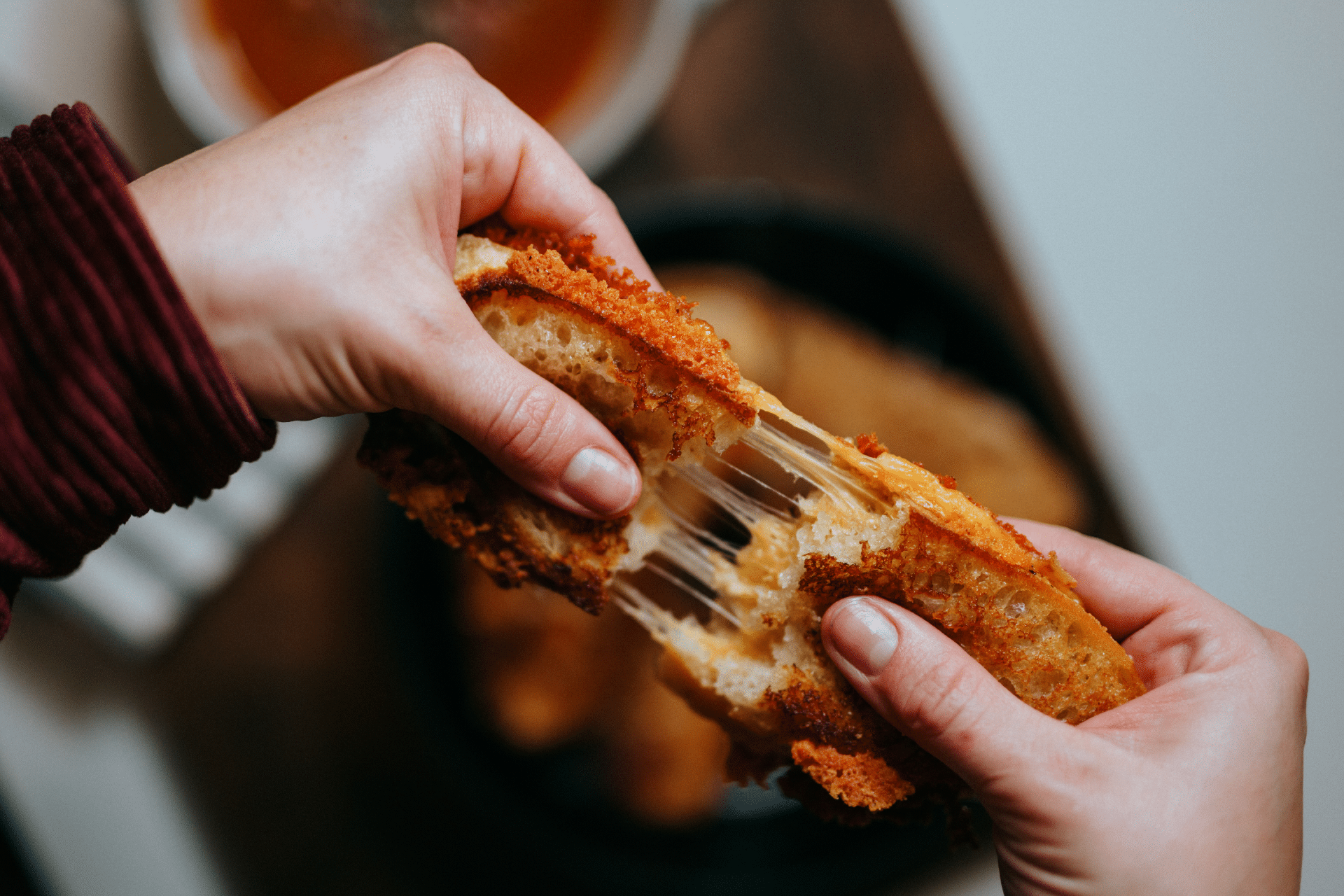 hands pulling apart a grilled cheese sandwich