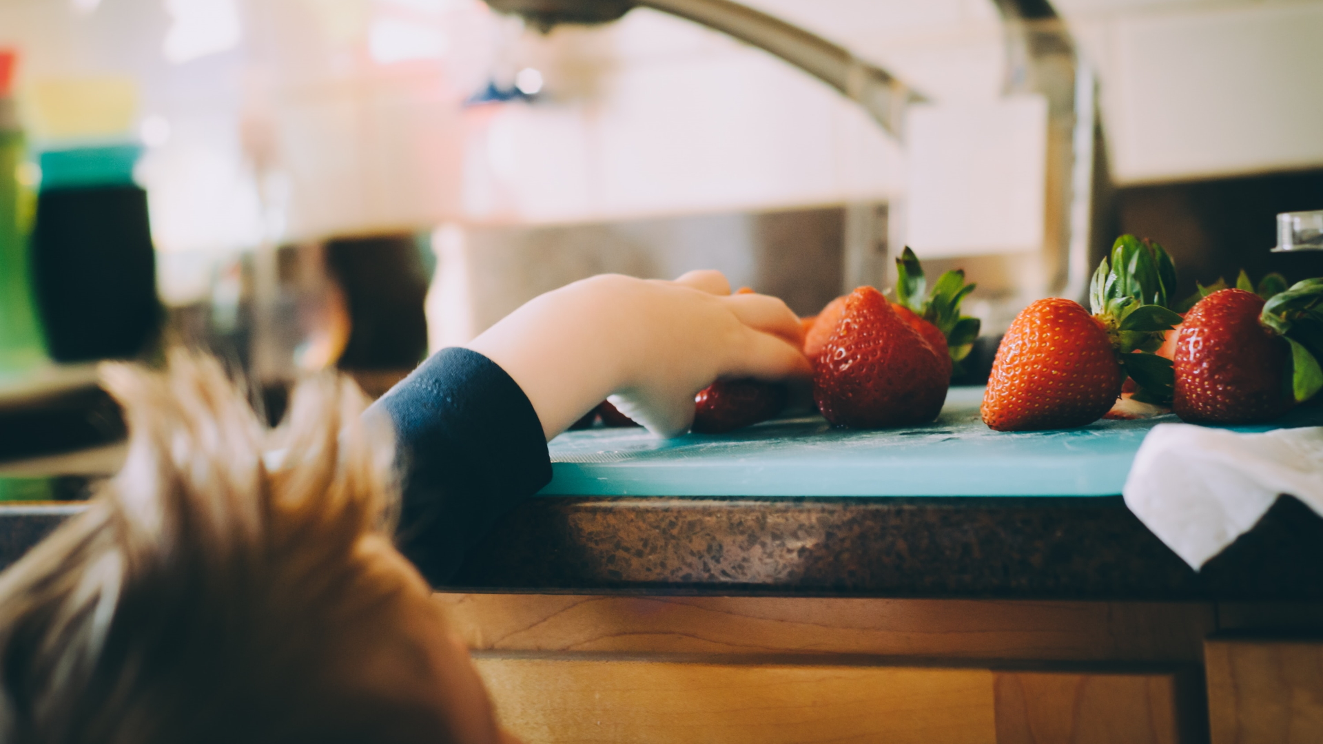 child reaching for strawberries