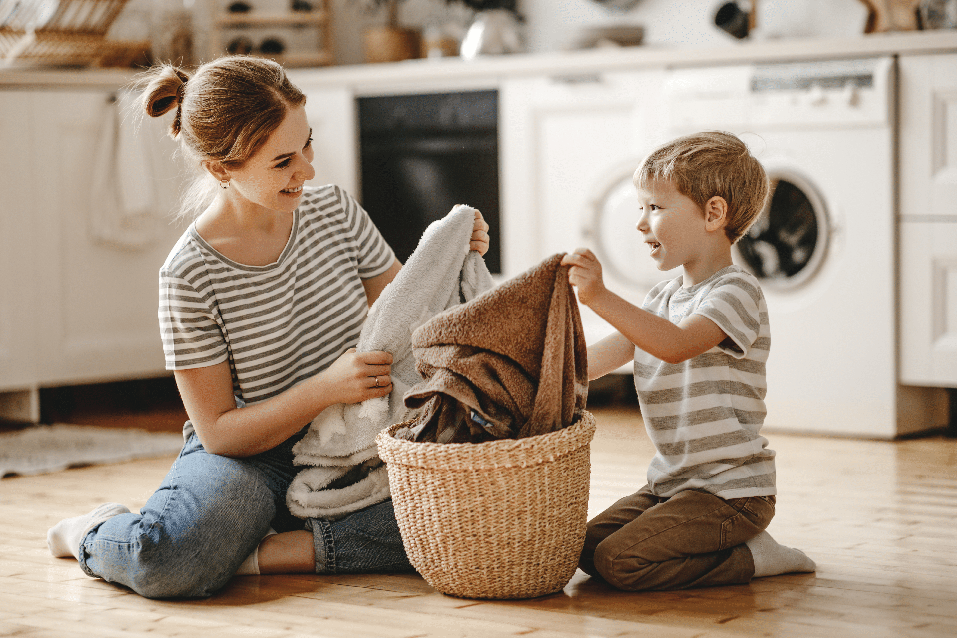 mother and child smile while folding laundry