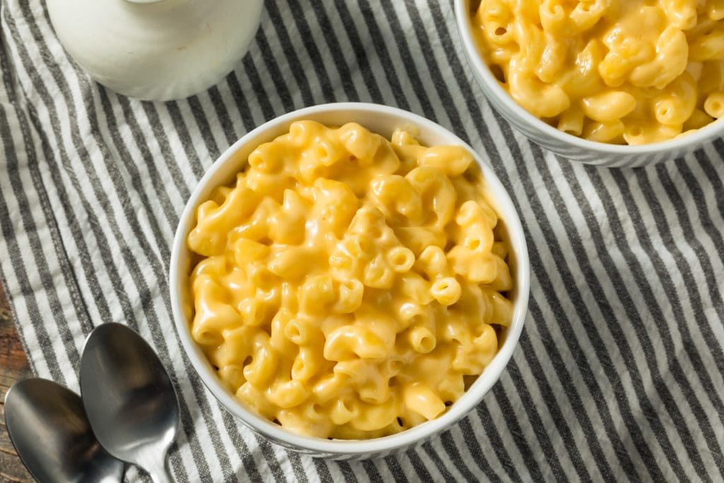 bowls of creamy macaroni and cheese on a striped table linen