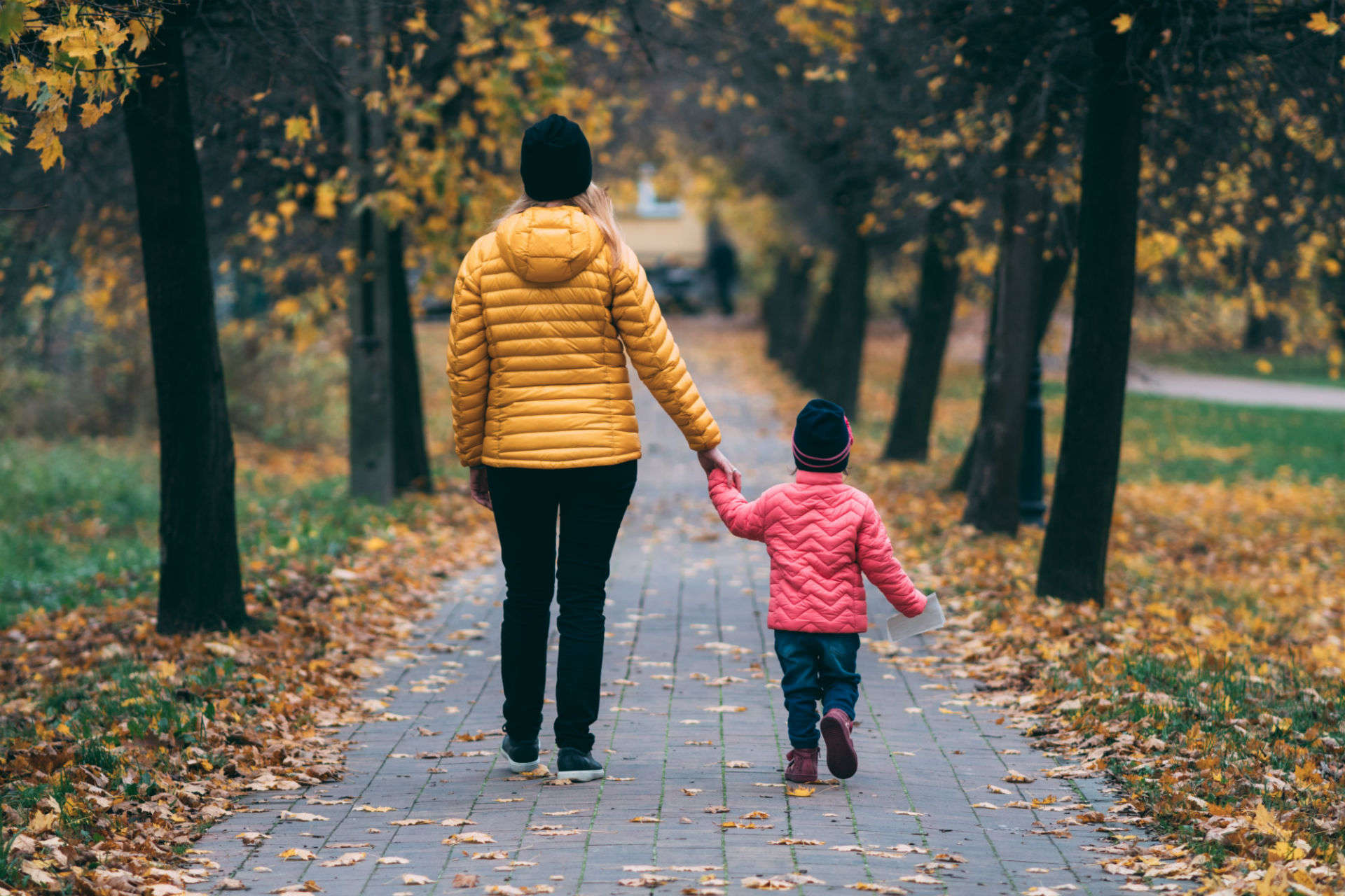 a mother and child walking down a path in the fall