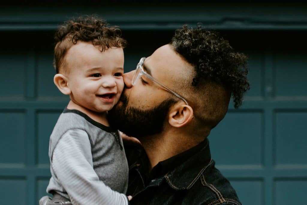 man kissing his toddler on the cheek