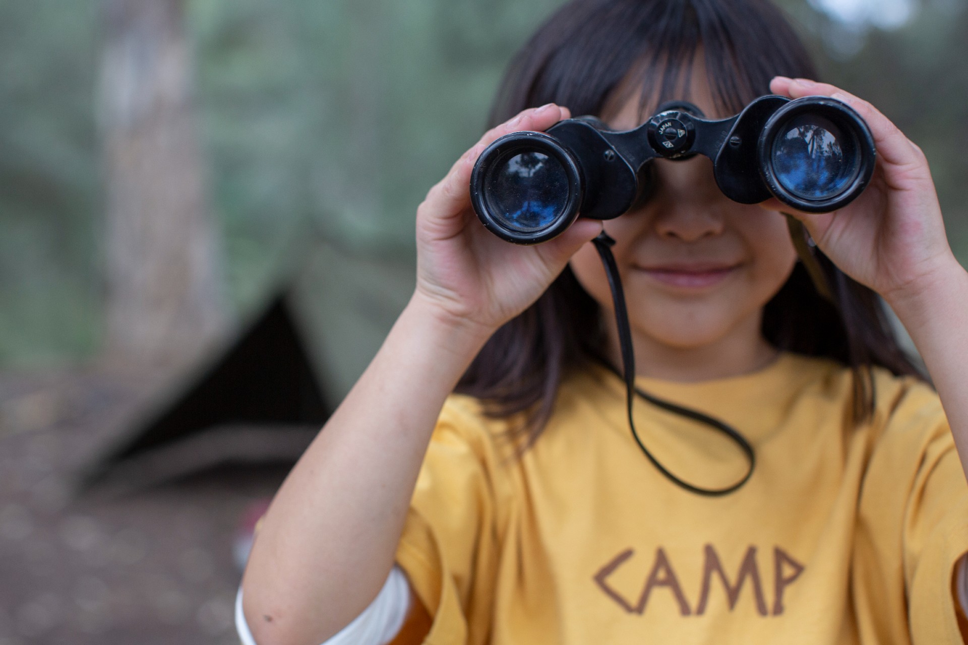 Little girl looks through binoculars at overnight camp