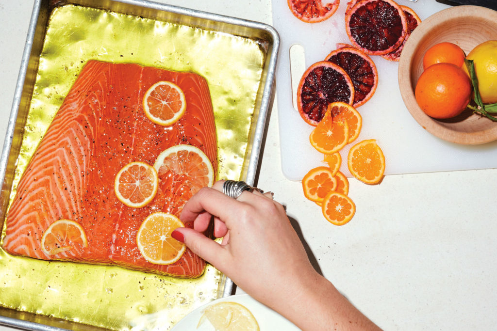 salmon on a sheet pan with citrus slices over it