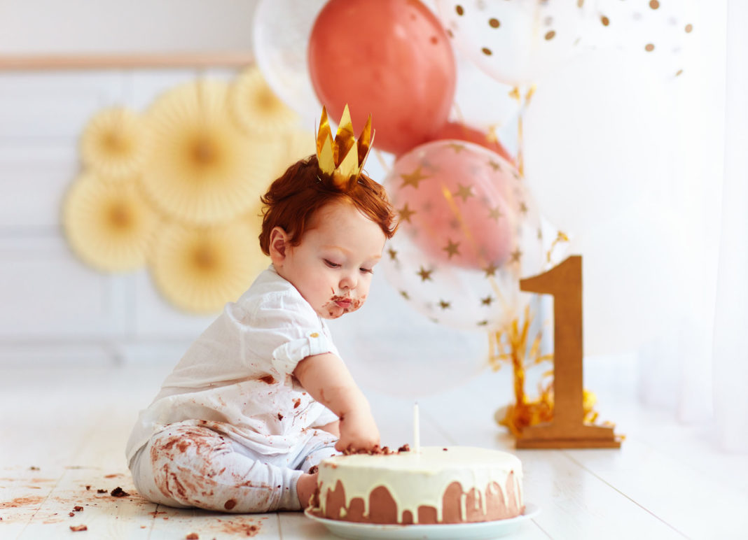 baby at first birthday with cake and balloons