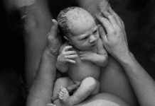 Is A Waterbirth Right For You? newborn baby on mother's stomach. Both are in a shallow pool