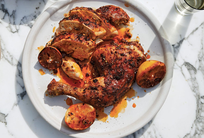 chicken covered in spice with wedges of lemon