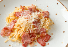 Easy Spaghetti Carbonara plate of spaghetti carbonara with thick pieces of bacon and a sprinkling of parmesan cheese