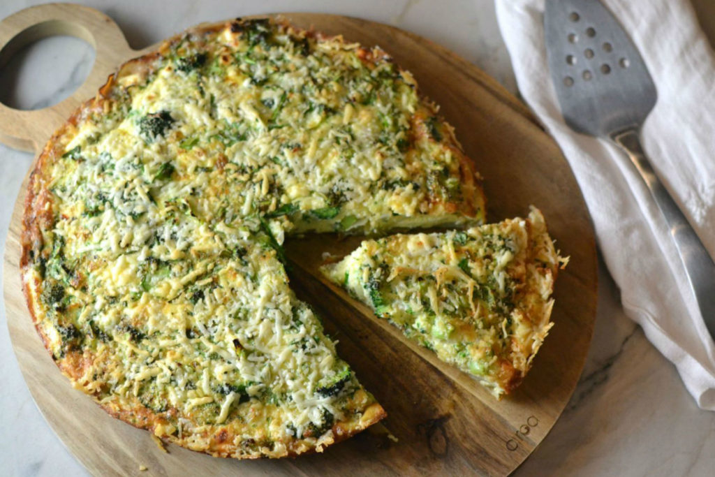 broccoli frittata on a wooden cutting board with a serving knife