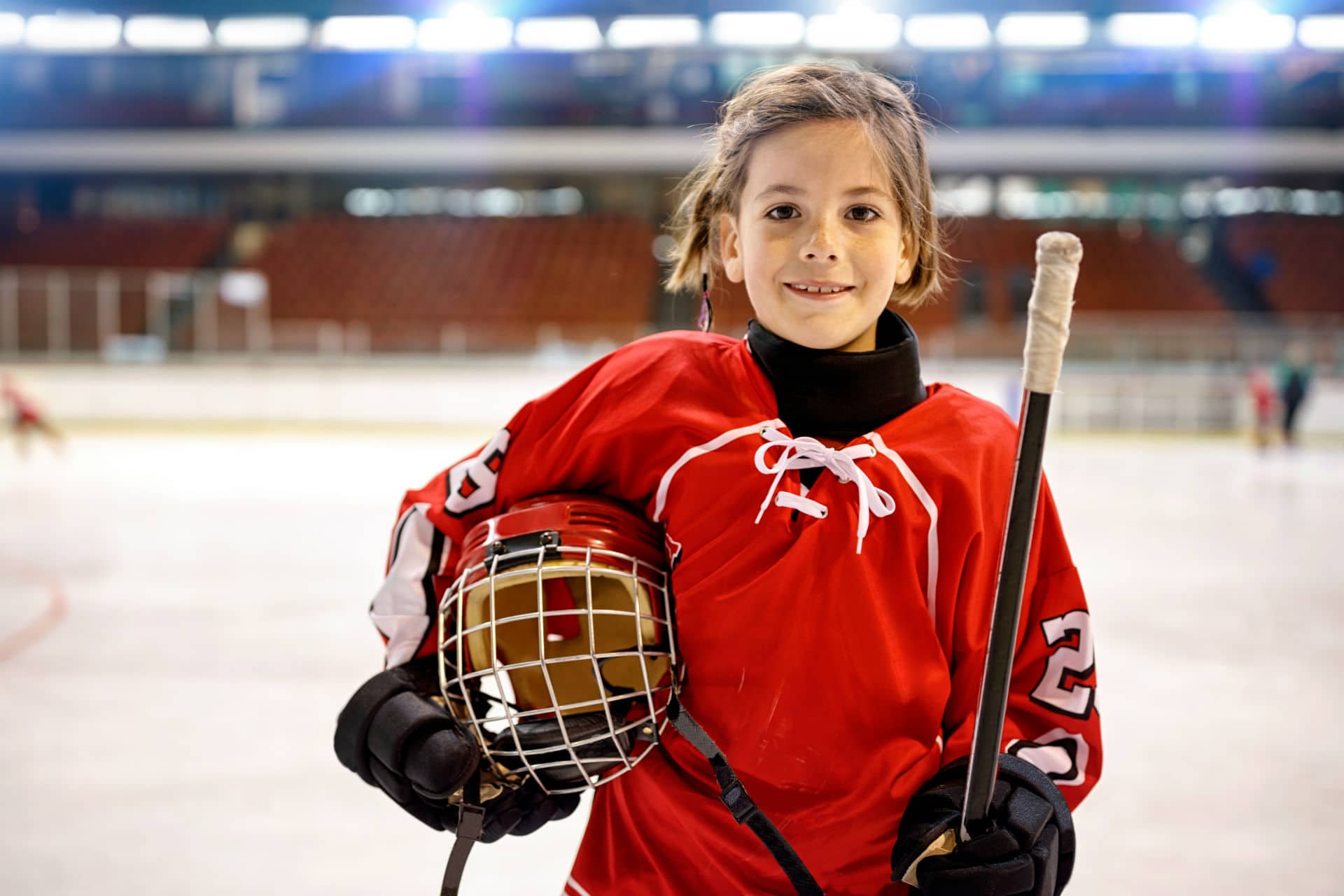 girl playing hockey with a helmet under her arm