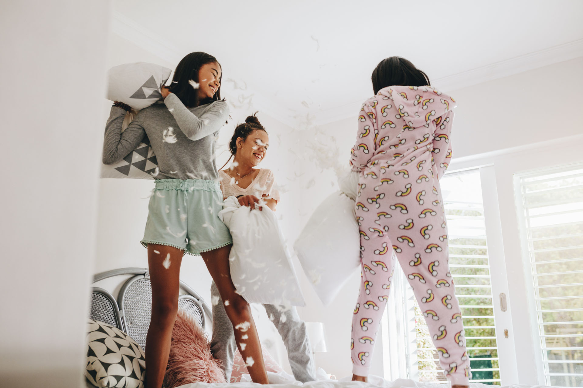 Girls pillow fighting standing on bed