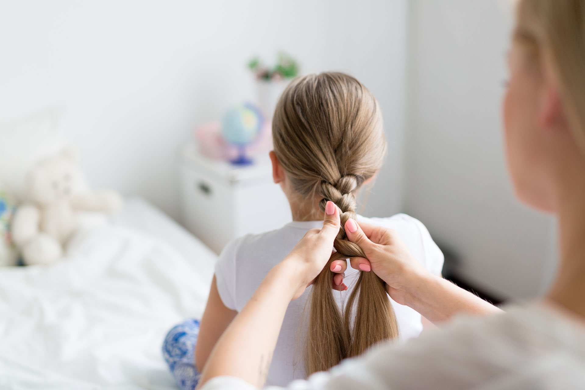 woman braiding her daughter's hair