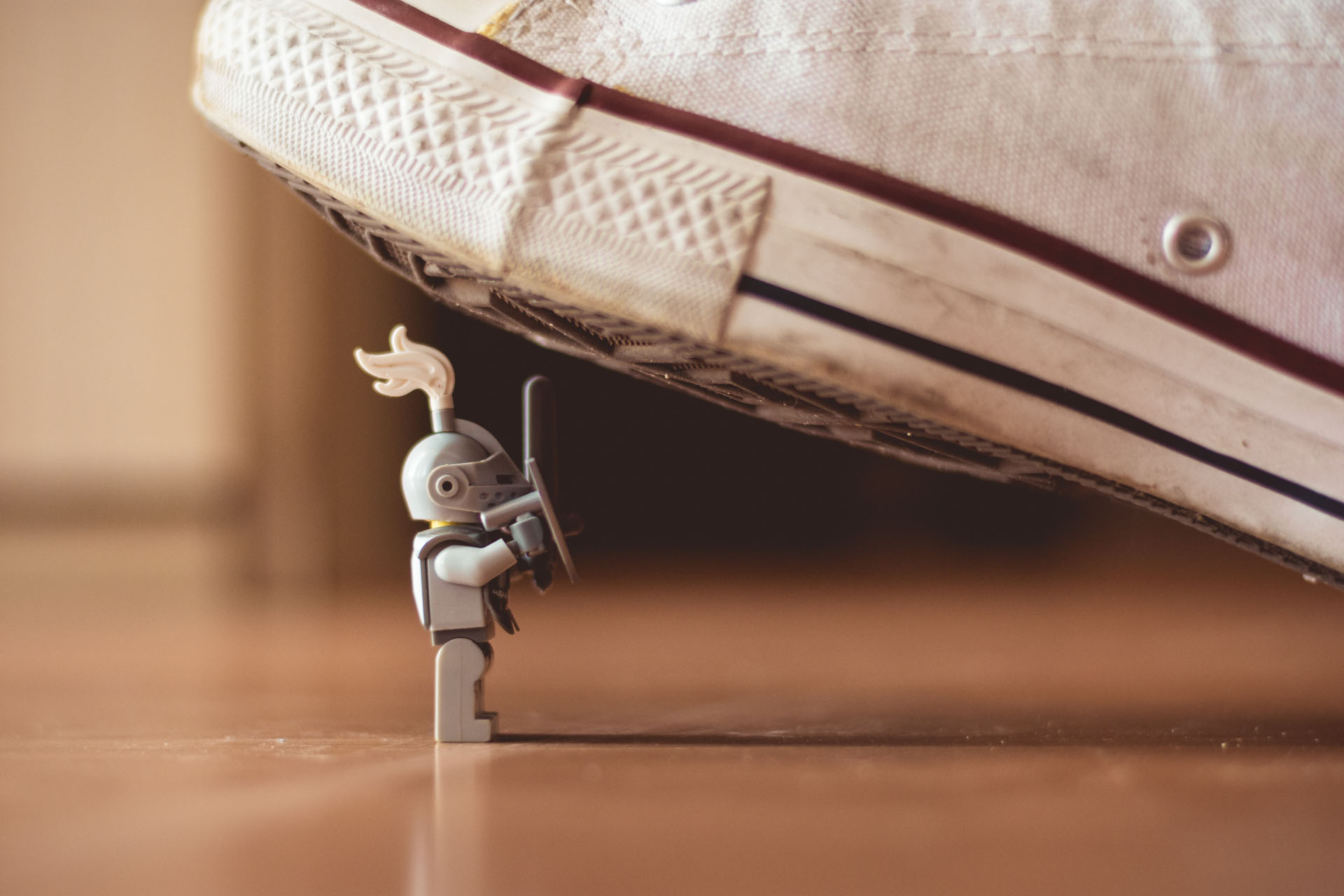 small lego knight showing resilience with a running shoe threatening to step on him