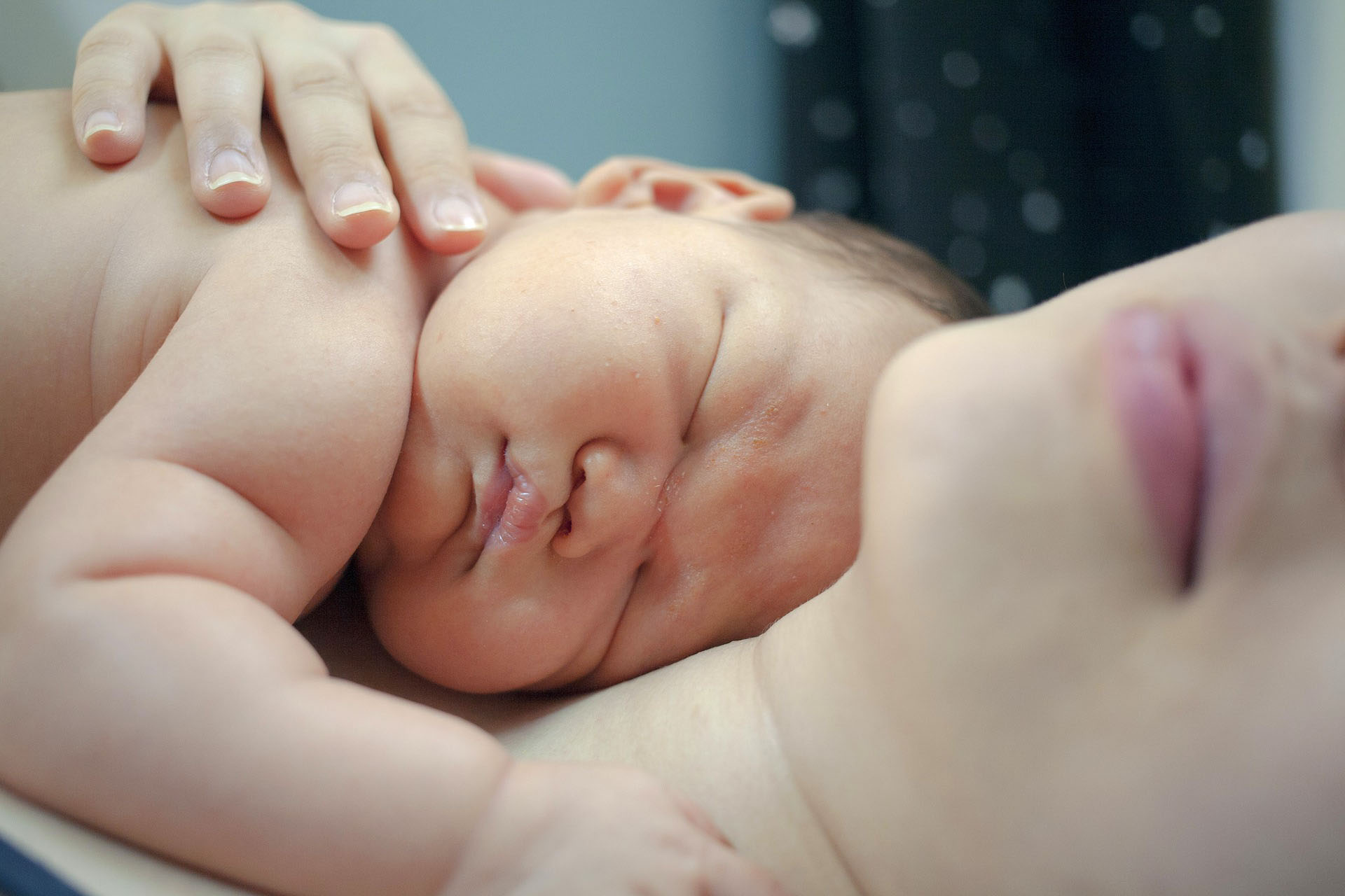 woman holding a newborn baby on her chest