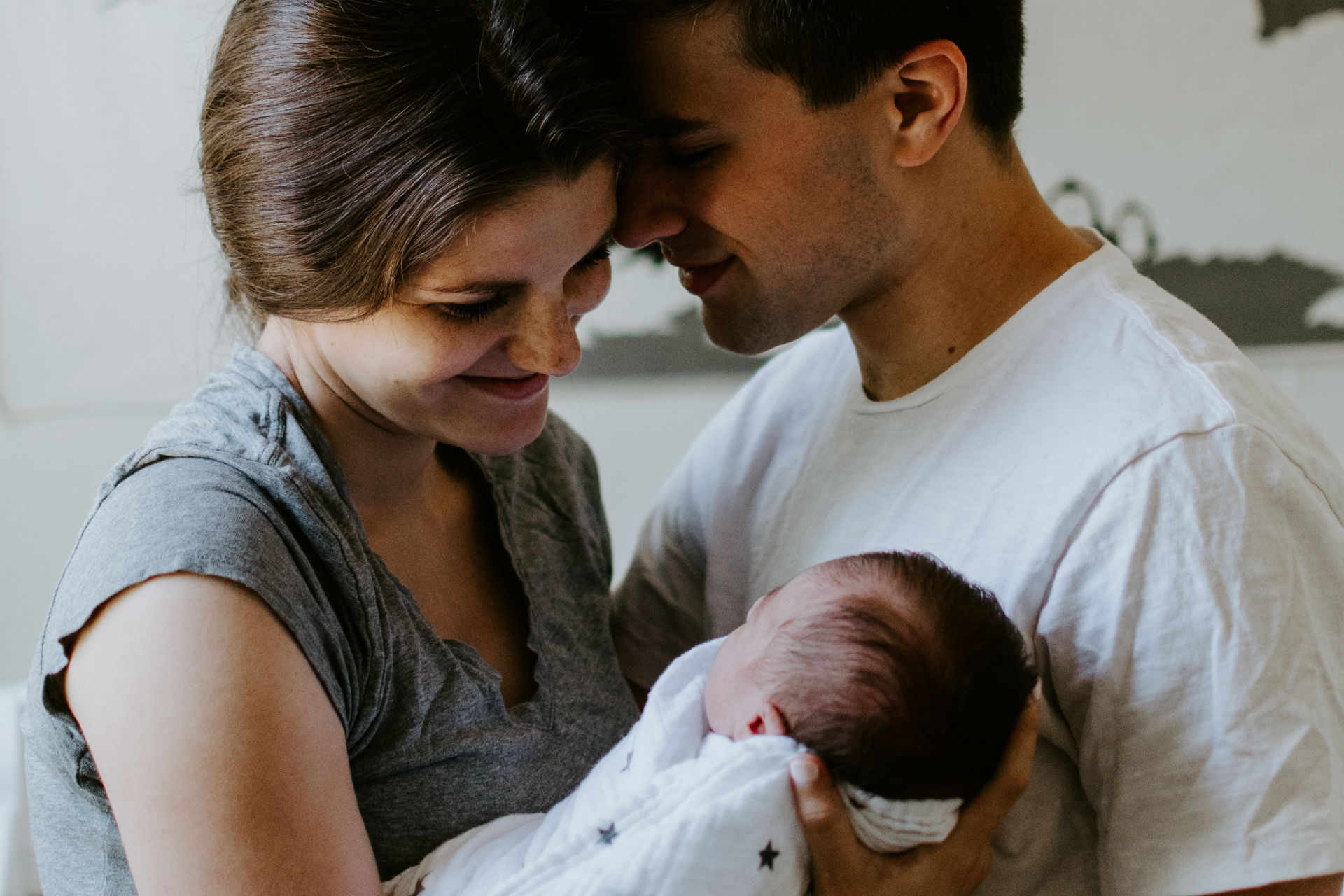 mom and dad holding their swaddled baby | becoming parents