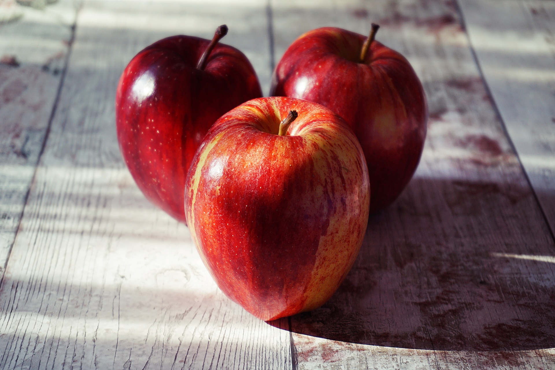 Three red apples on a wooden tabletop