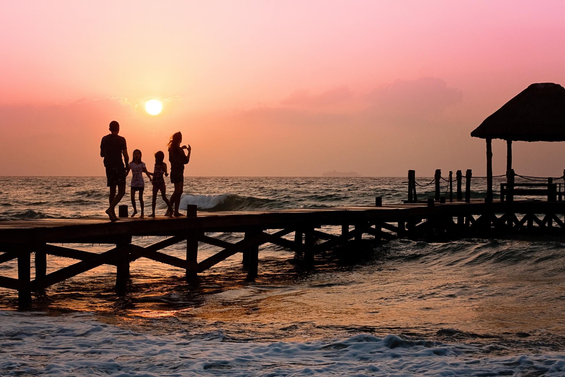 Family walking on a dock with sunset in distance