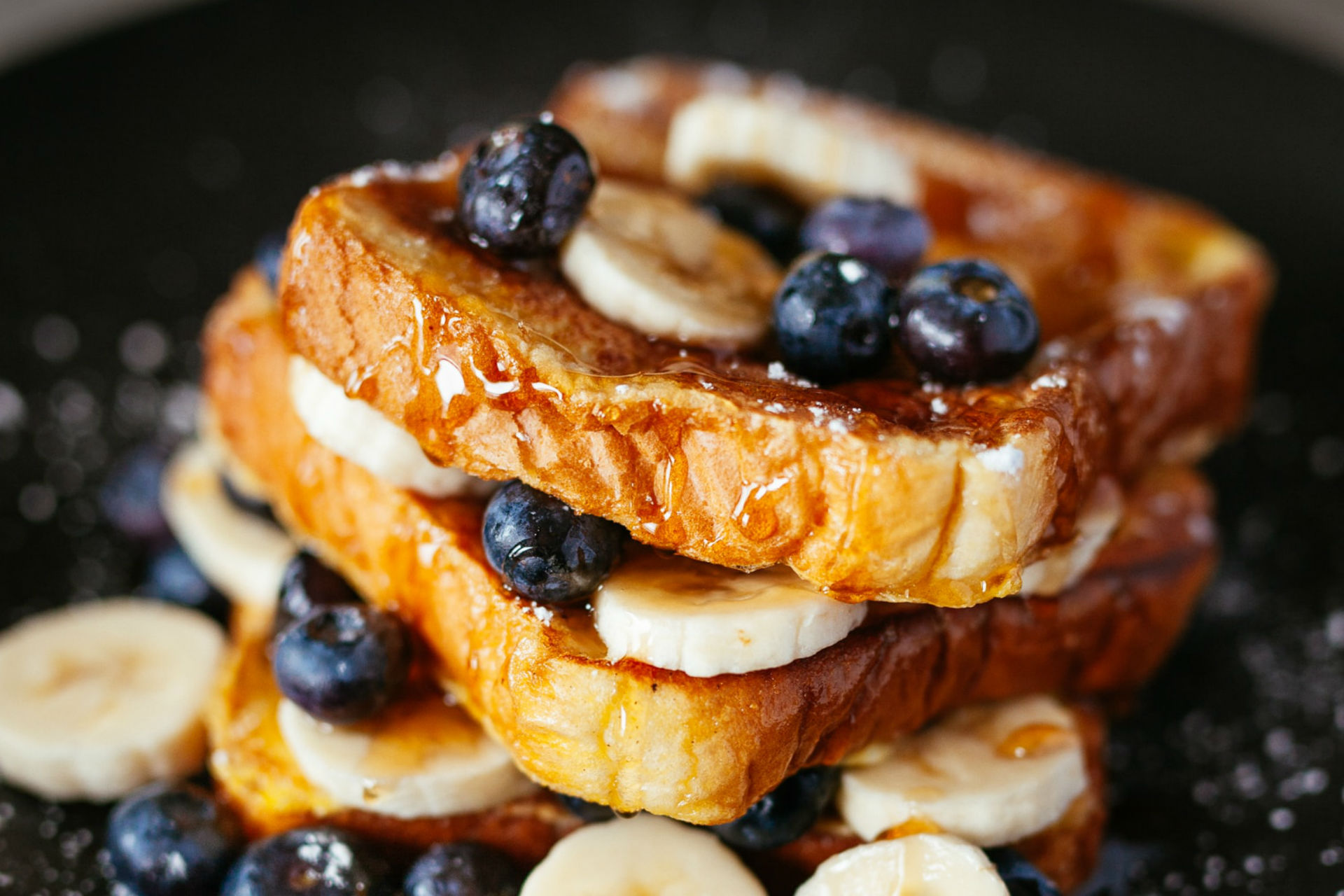 stack of french toast with bananas and blueberries