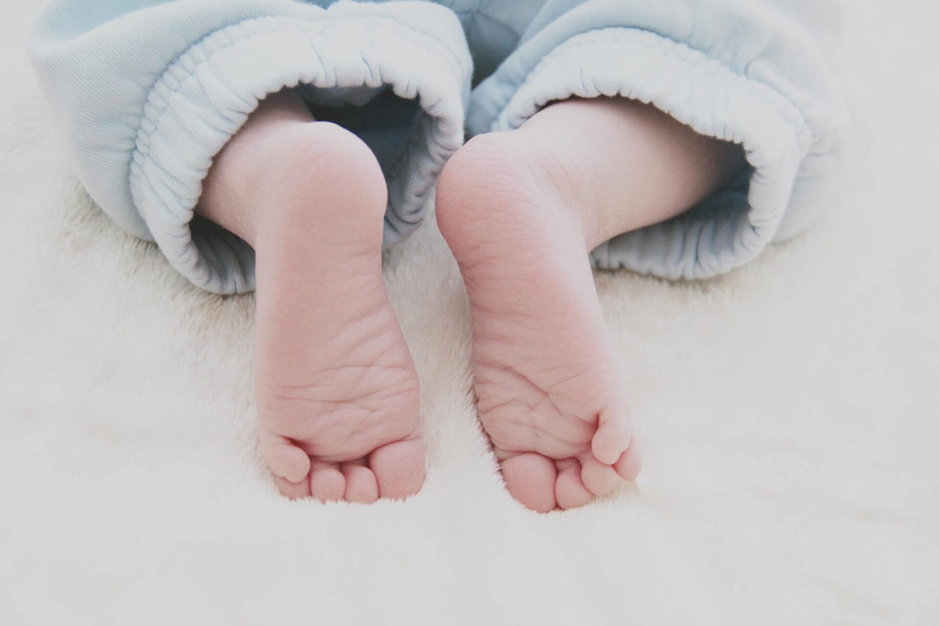Feet of a baby wearing grey-blue trackpants
