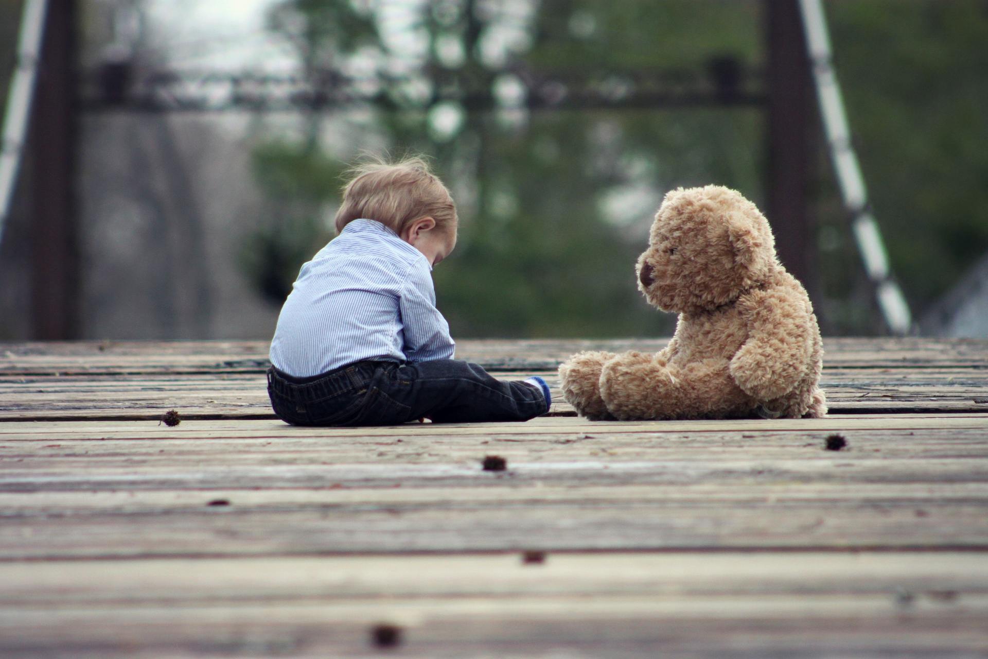 Toddler sitting alone with a teddy bear