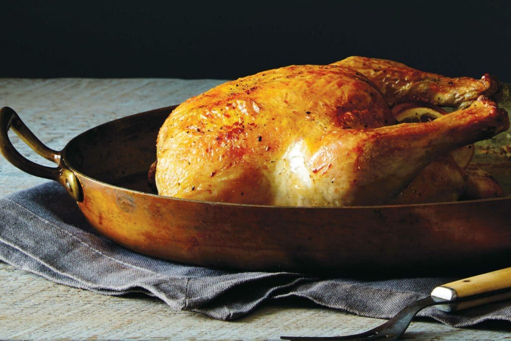 roast chicken sitting in a copper pan