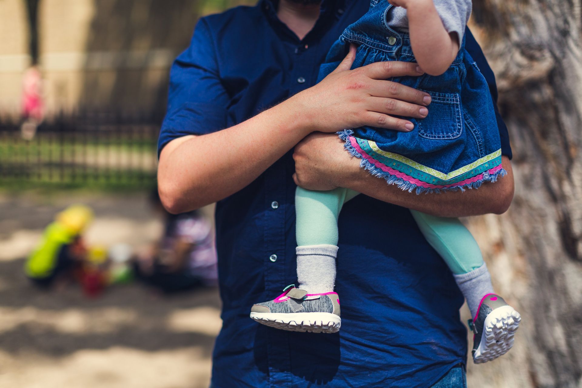 Parent holding child, focus on grey and pink sneakers