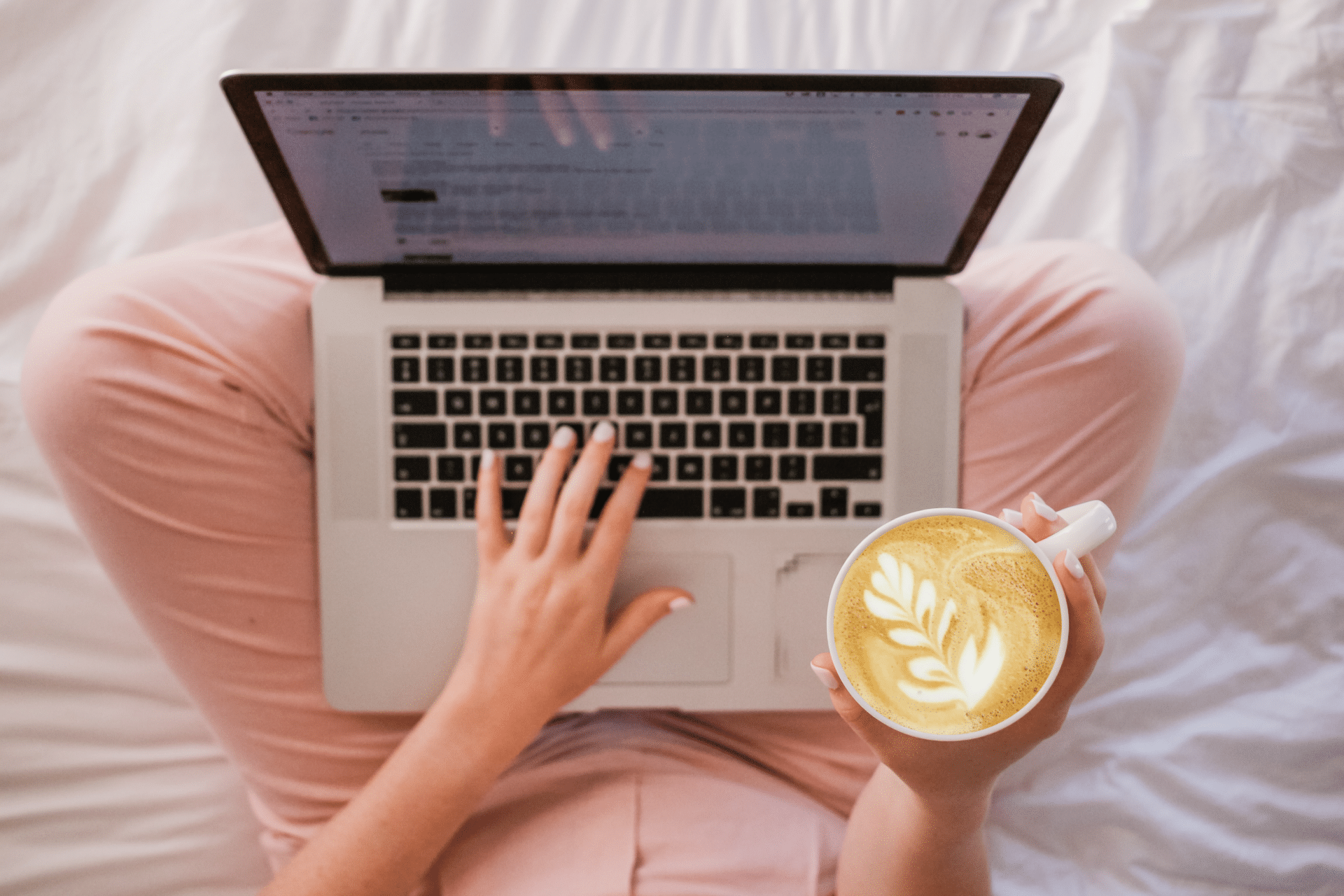 woman in pink pants with a latte and laptop
