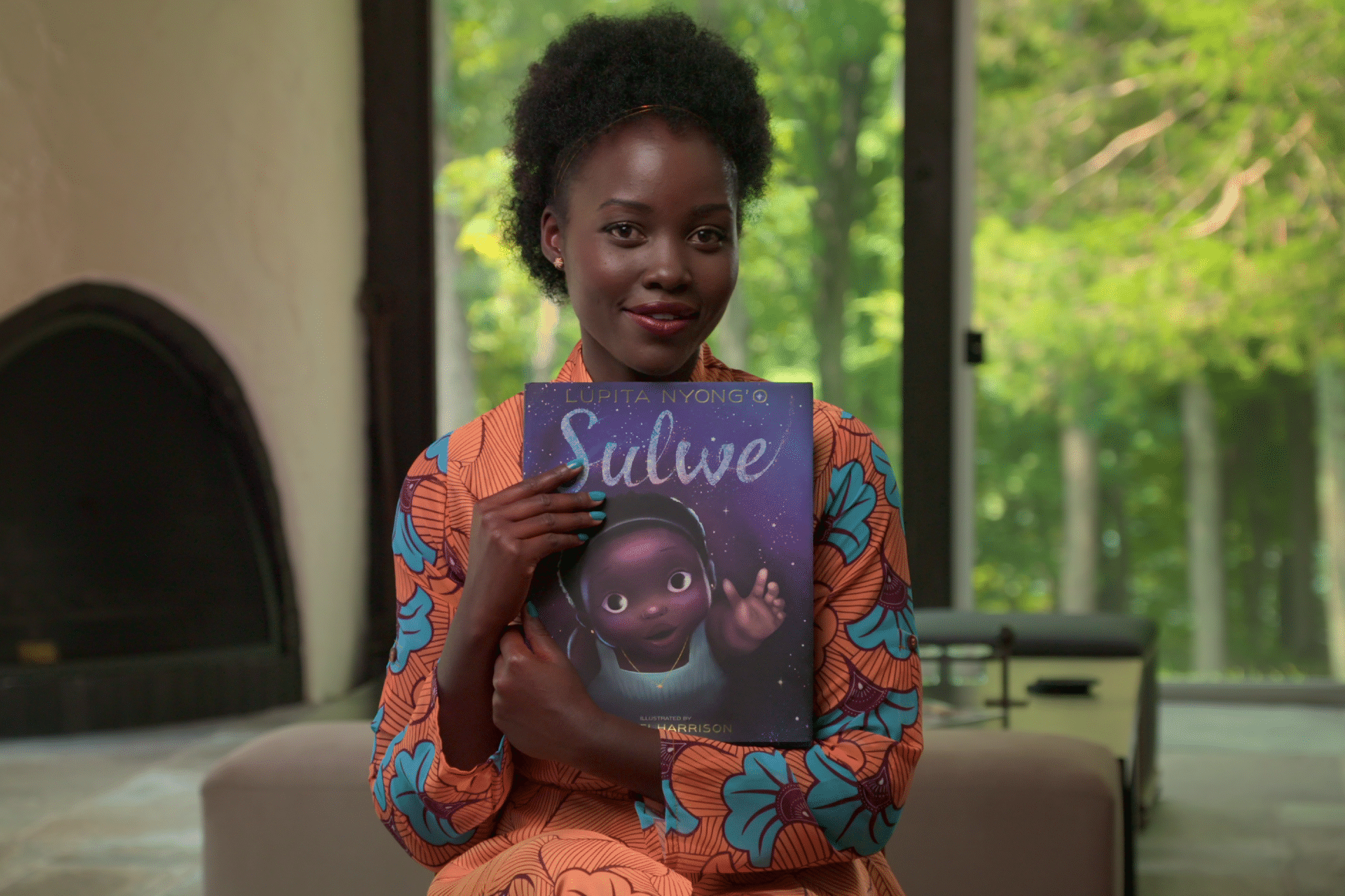 lupita holds up a children's book that she wrote