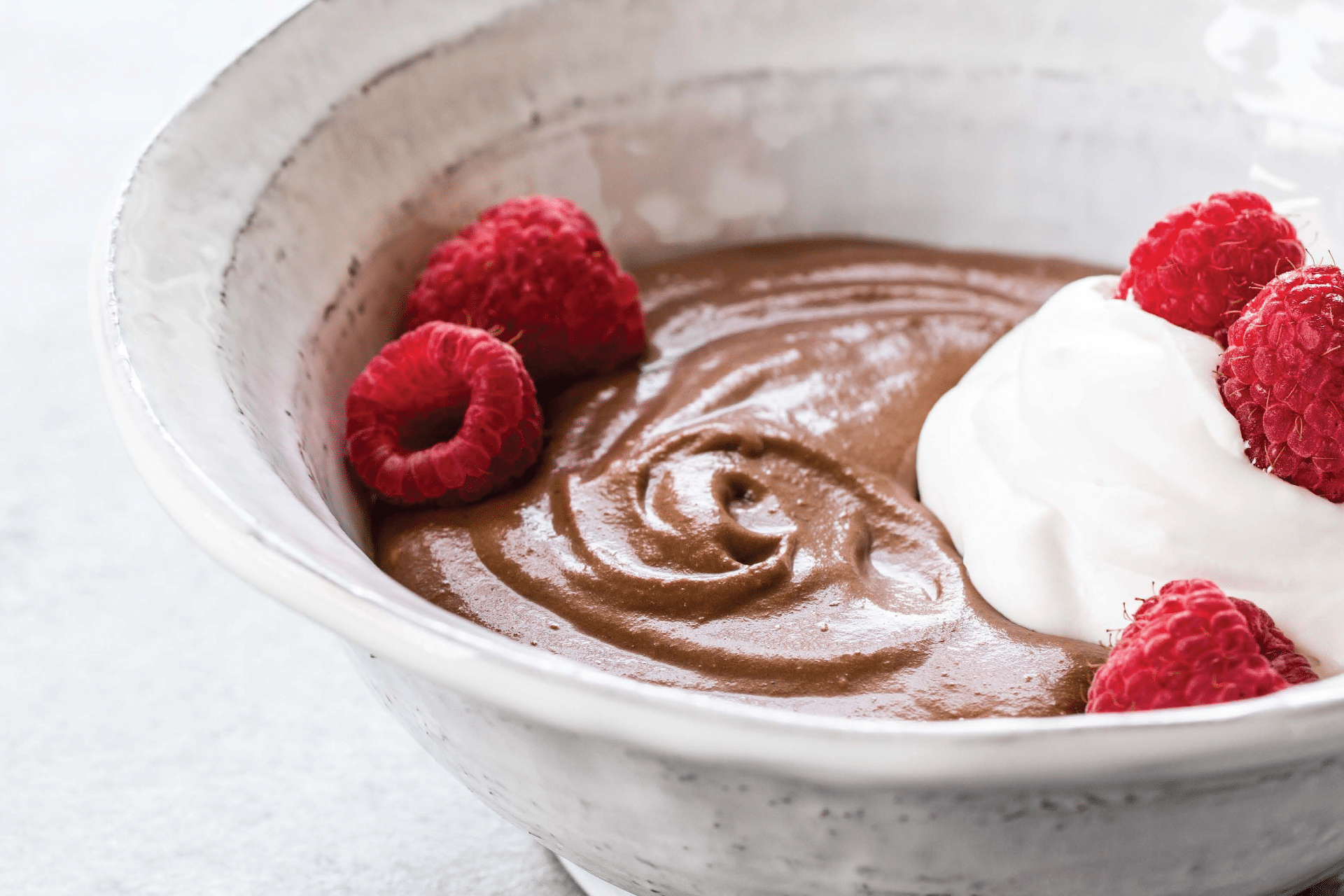 Bowl of chocolate pudding with whipped cream and raspberries