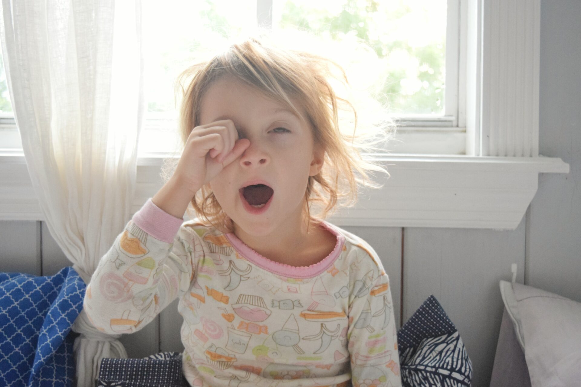 child yawning and rubbing eye in the morning