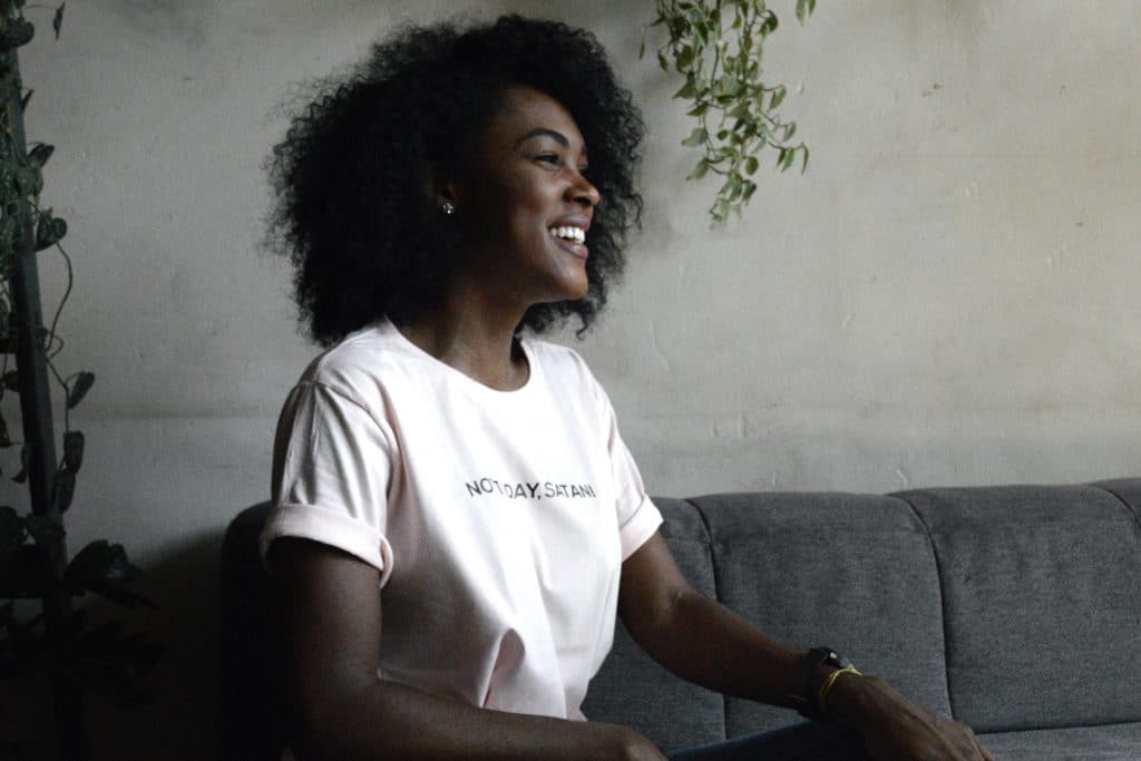 a Black woman sits on a couch looking away from the camera