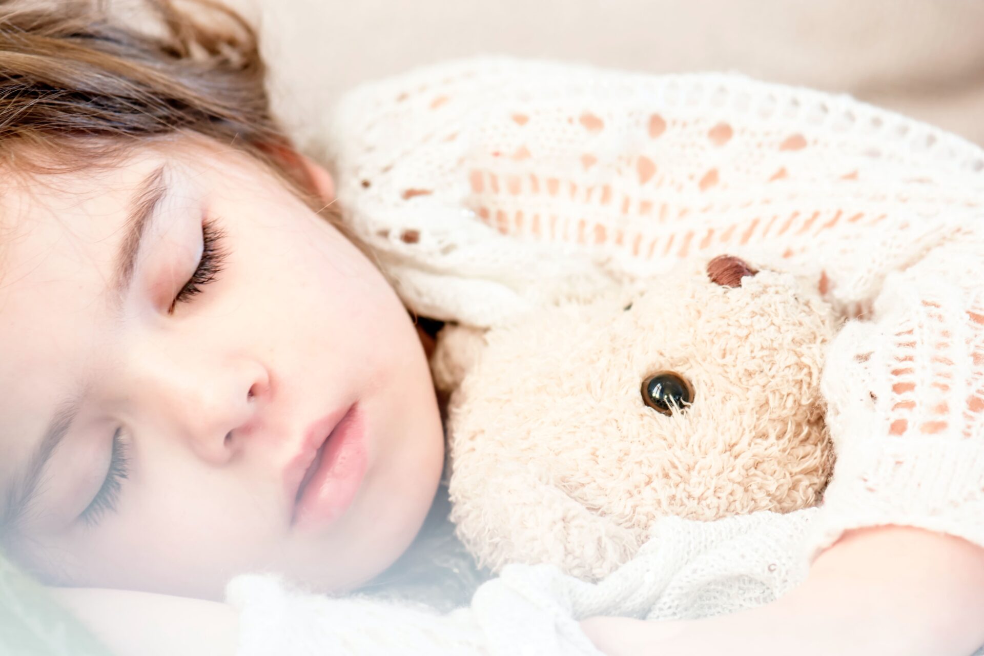 sleeping child while holding a teddy bear