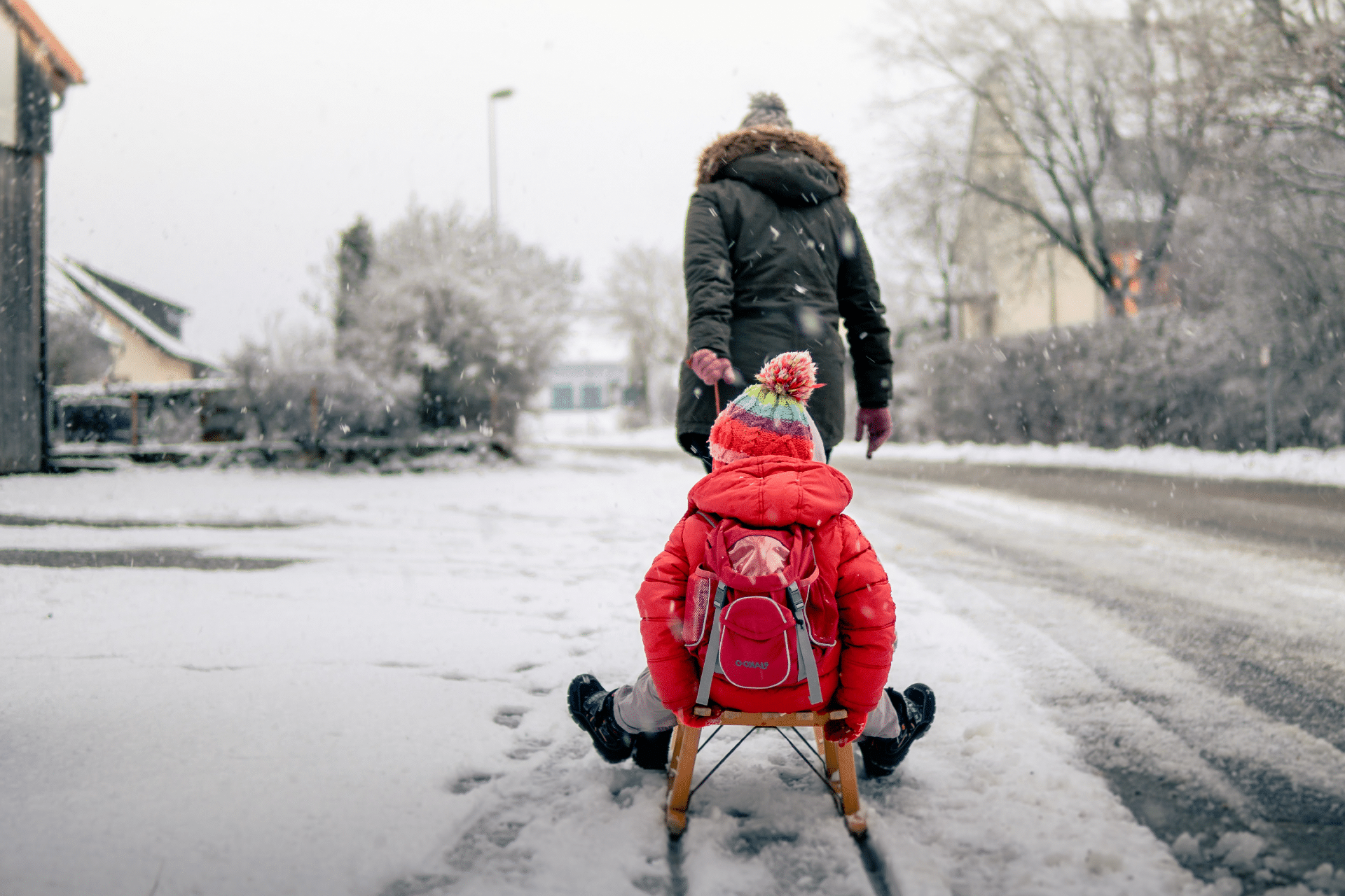 woman pulling girl on a sled