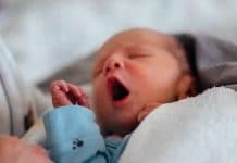 Why Swaddling Newborns Is No Longer Recommended newborn baby yawing while being held