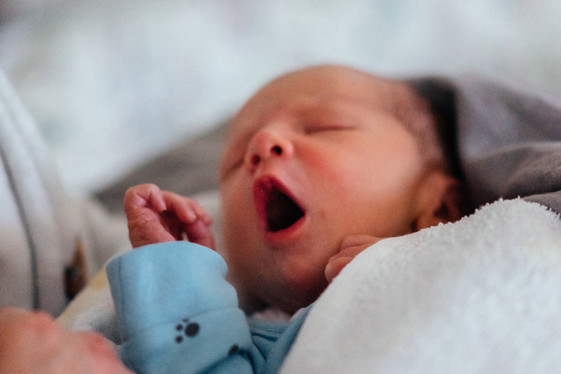 newborn baby yawing while being held