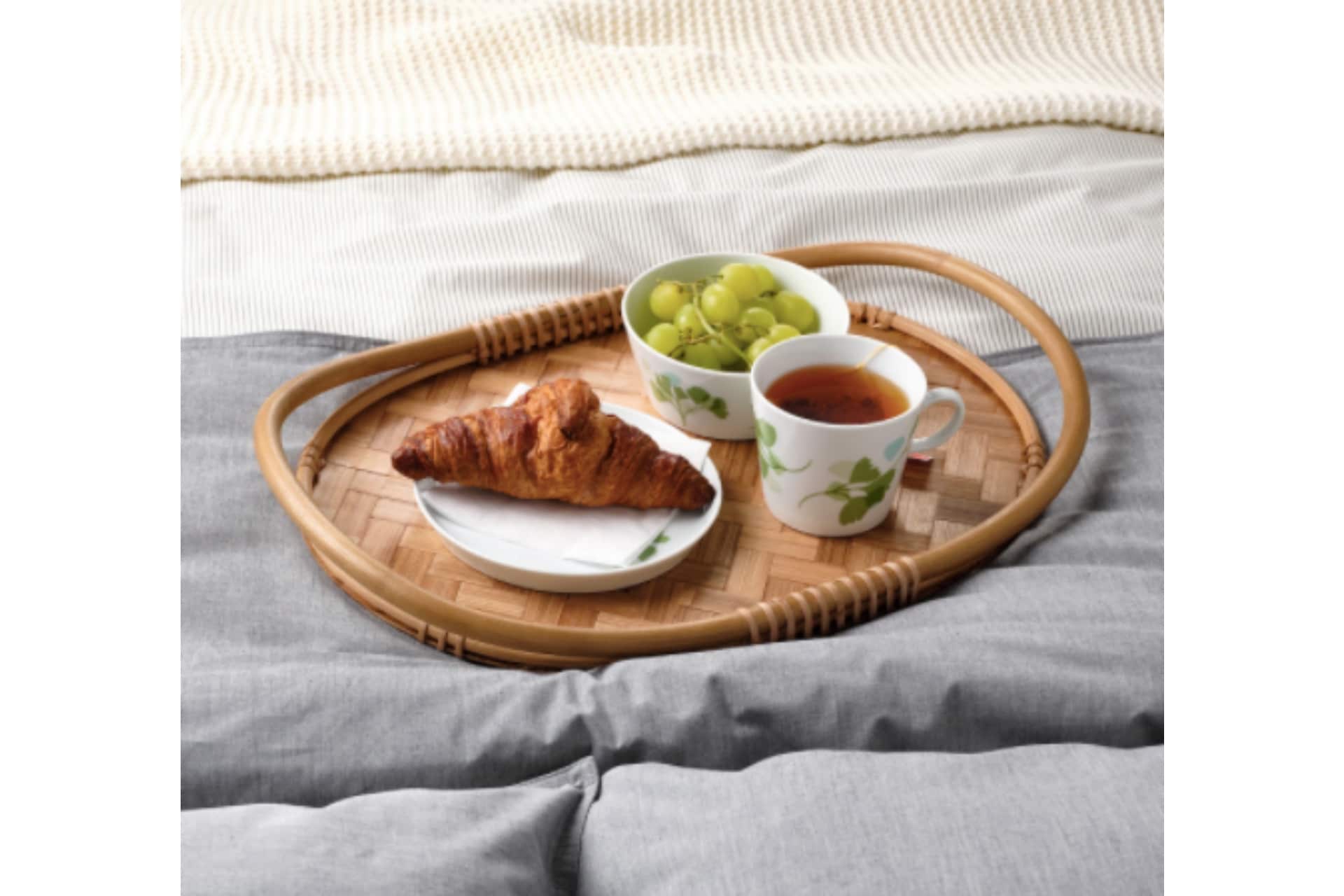bamboo tray with a croissant, fruit and tea on it
