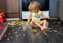 How To Deal When Your School-Age Child Seems Out Of Control little girl sits on the kitchen floor with dumped crackers scattered all over