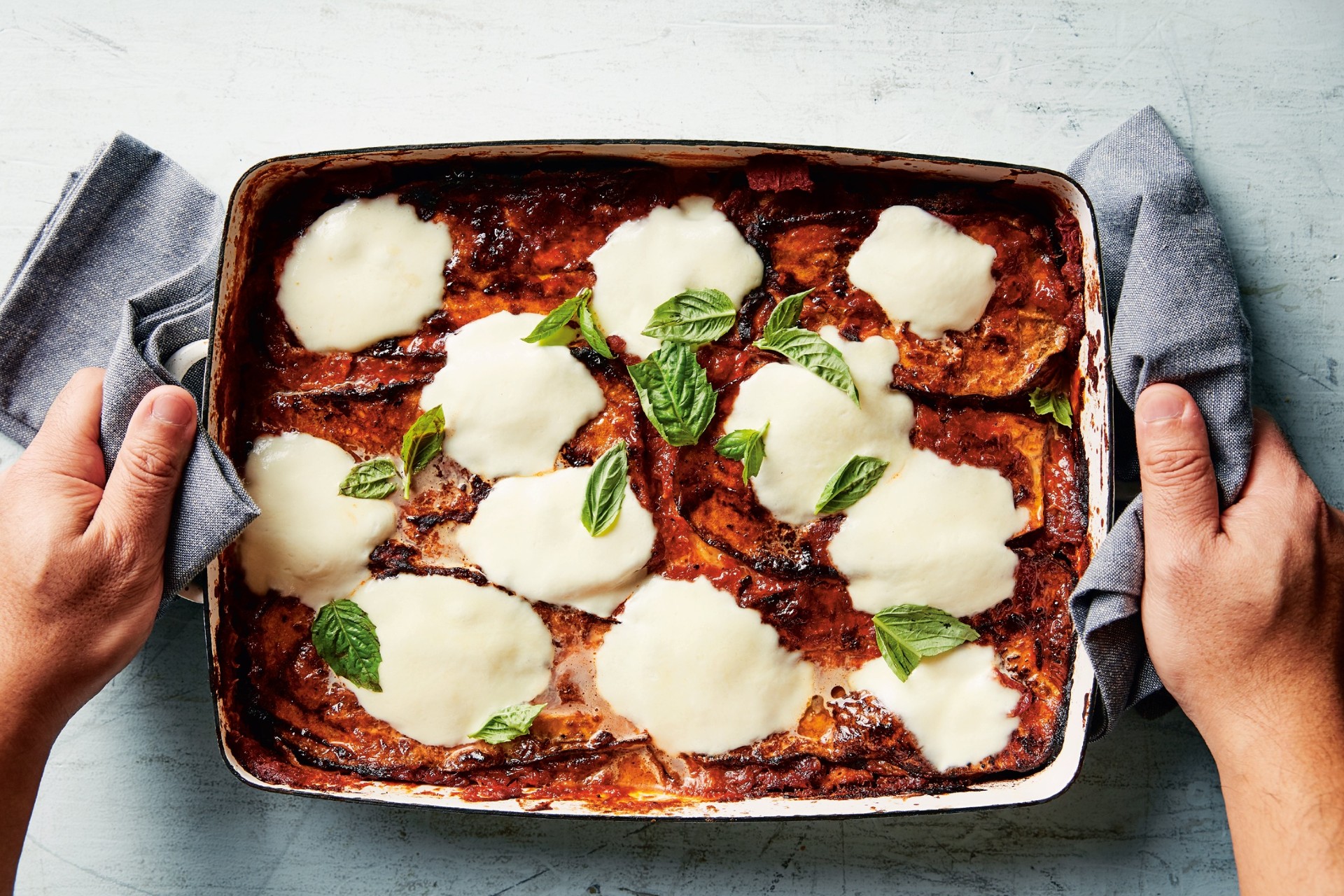 Casserole dish filled with eggplant parmesan and topped with melted cheese