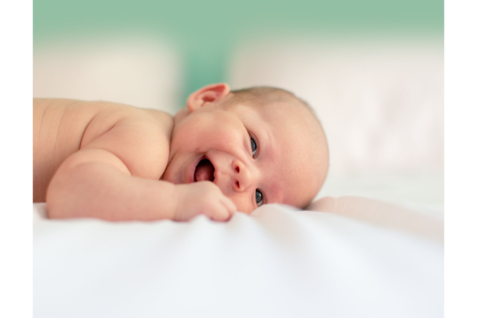 Newborn smiling, lying on a white sheet