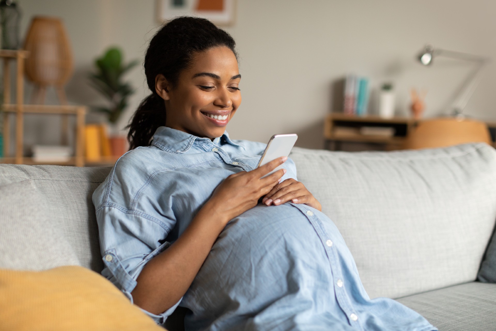 pregnant woman in final trimesters of pregnancy looking down on phone