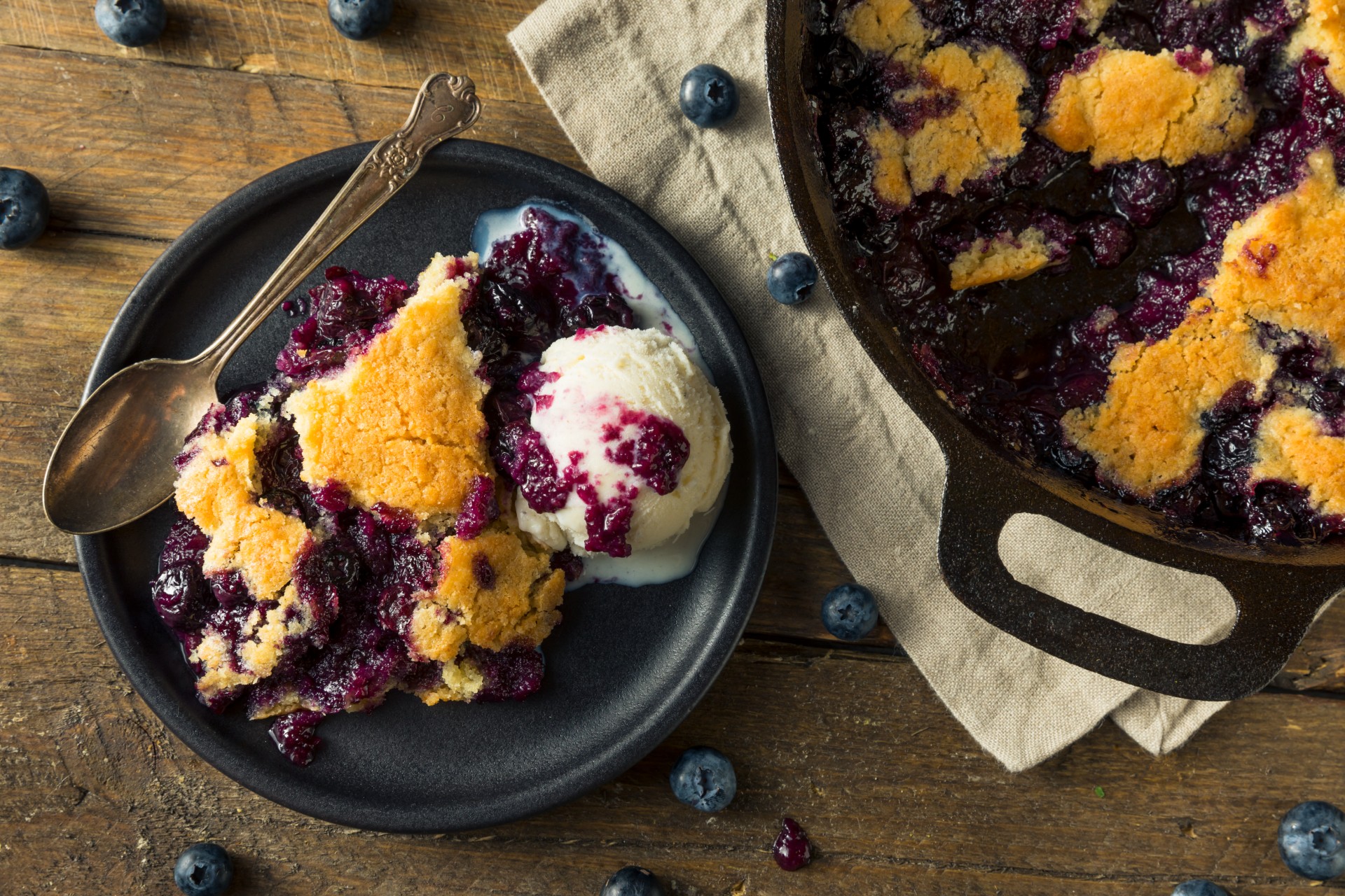 berry cobbler in a skillet with vanilla ice cream