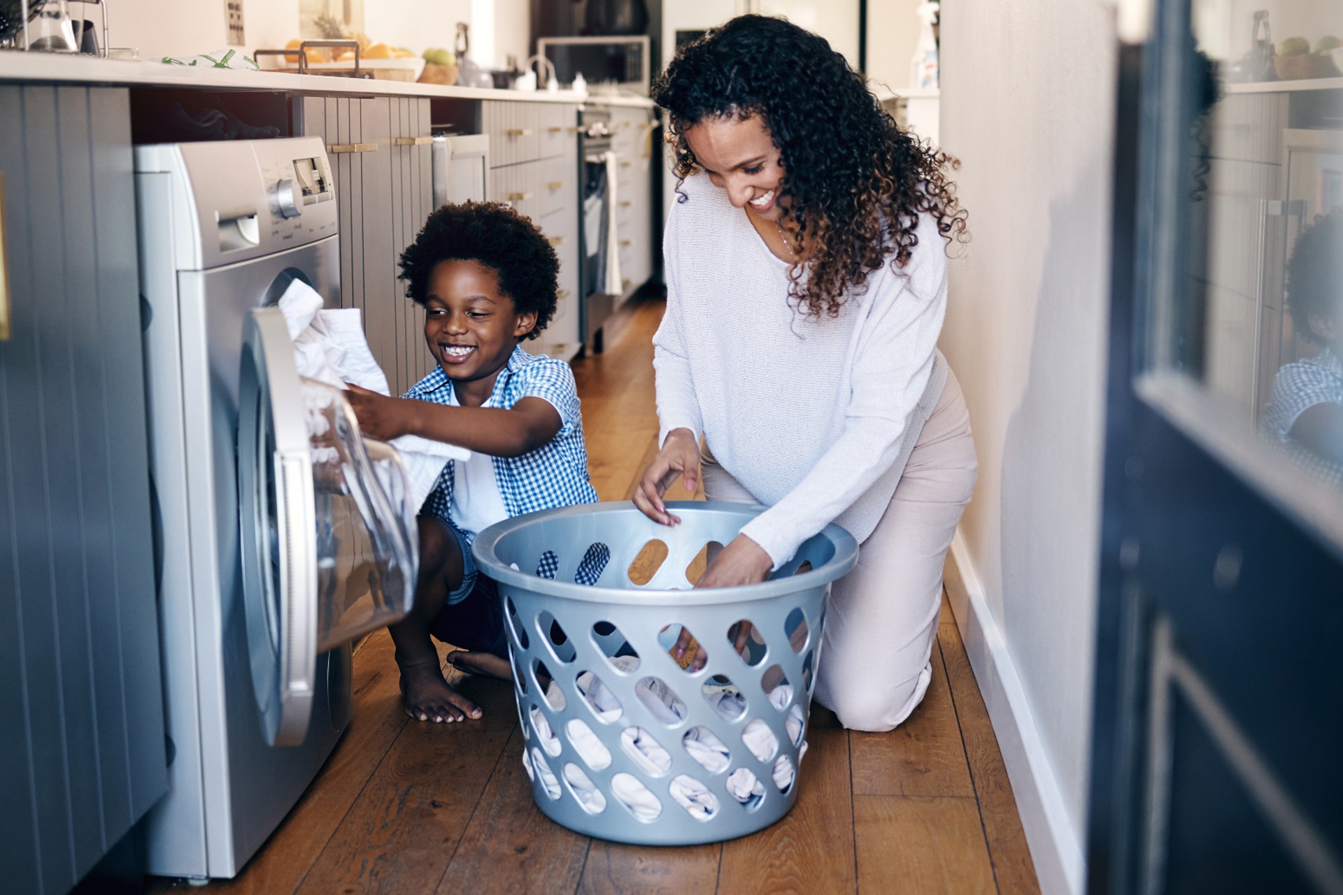 parent and child working on laundry together looking happy