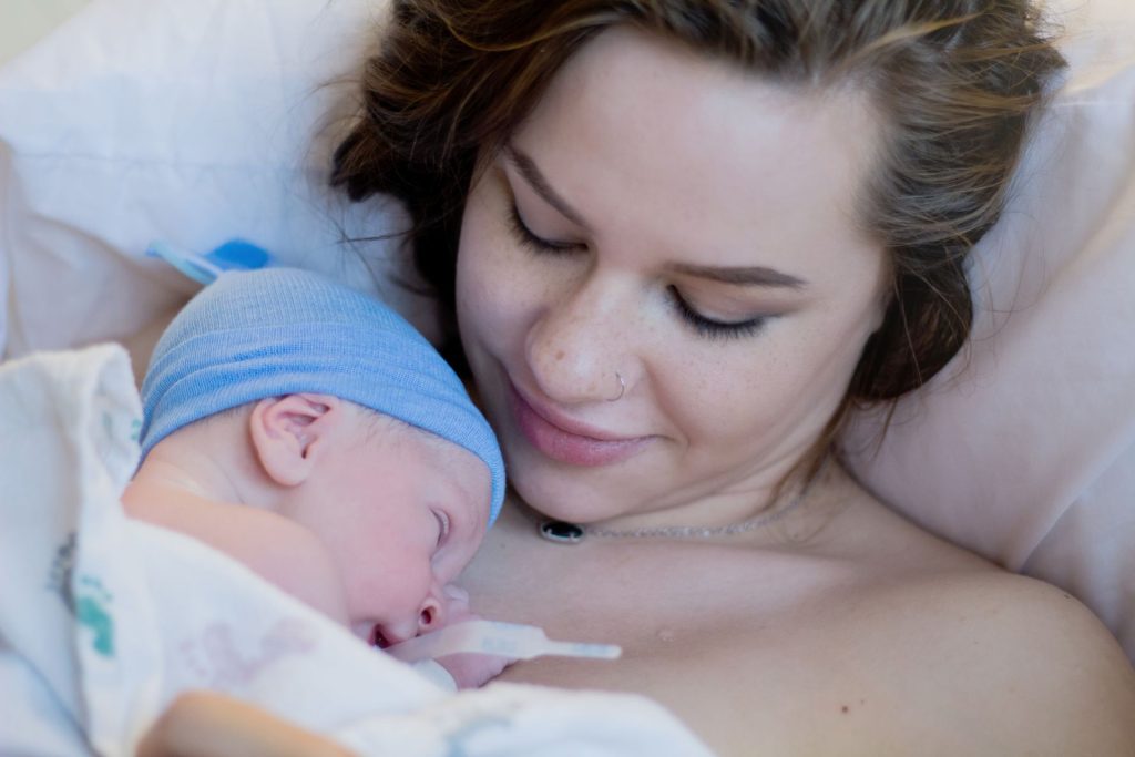 Woman with labour makeup holding newborn
