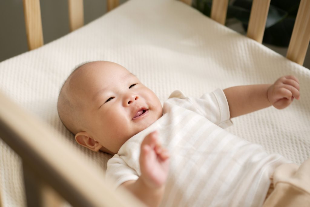 baby in a crib smiles up at their parent